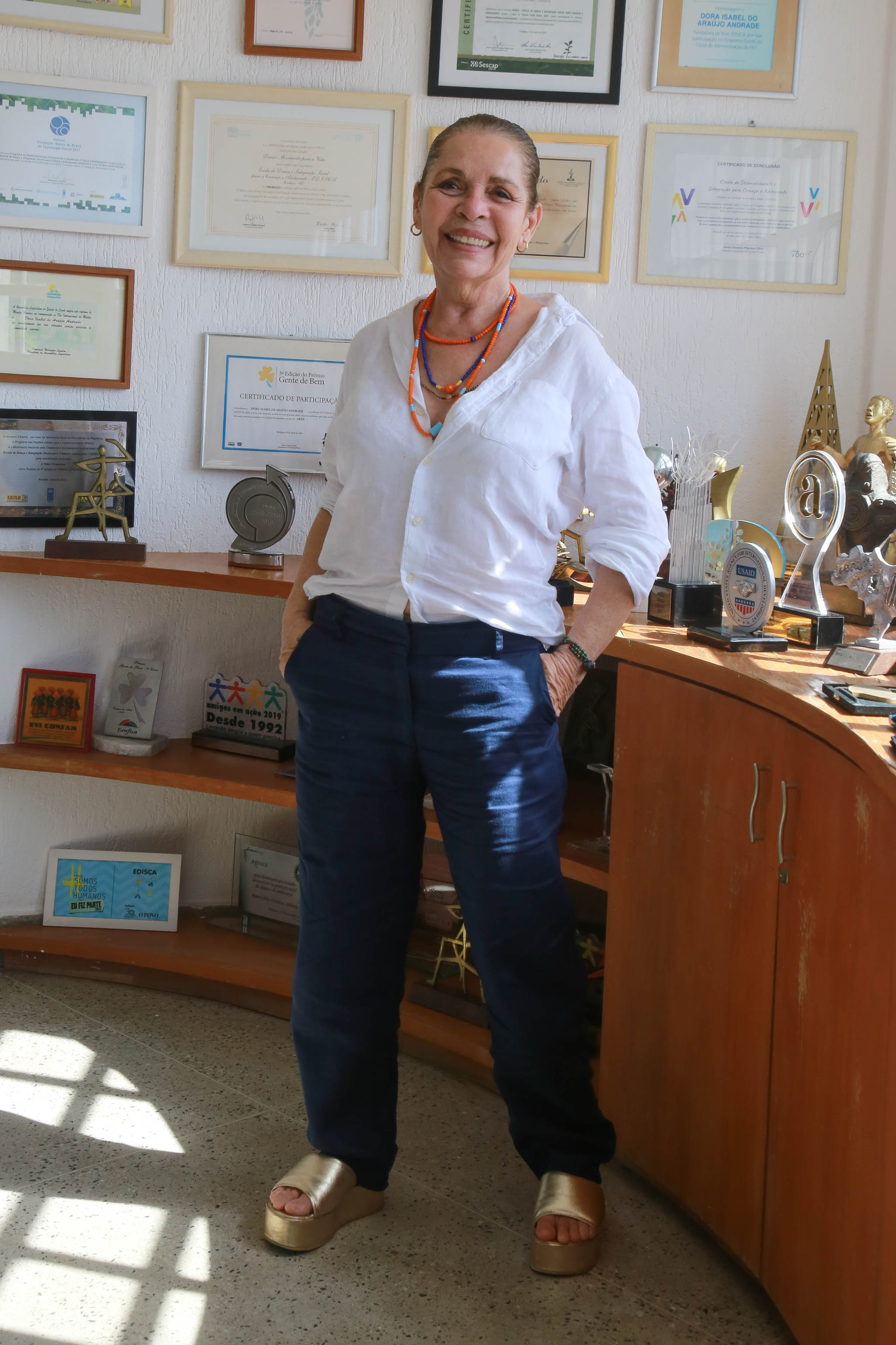 Dora Andrade posa para a foto em pé no seu escritório